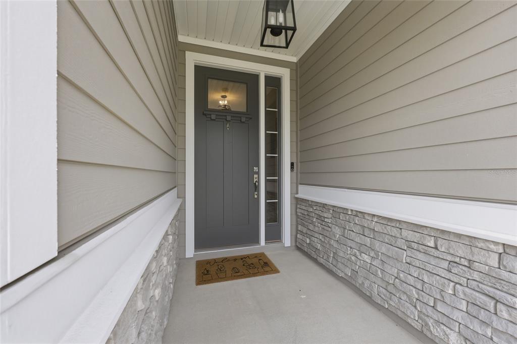 A covered entryway features a gray front door with a sidelight, stone siding, and horizontal cladding — 192 GOLDENROD DRIVE, ST AUGUSTINE, FL