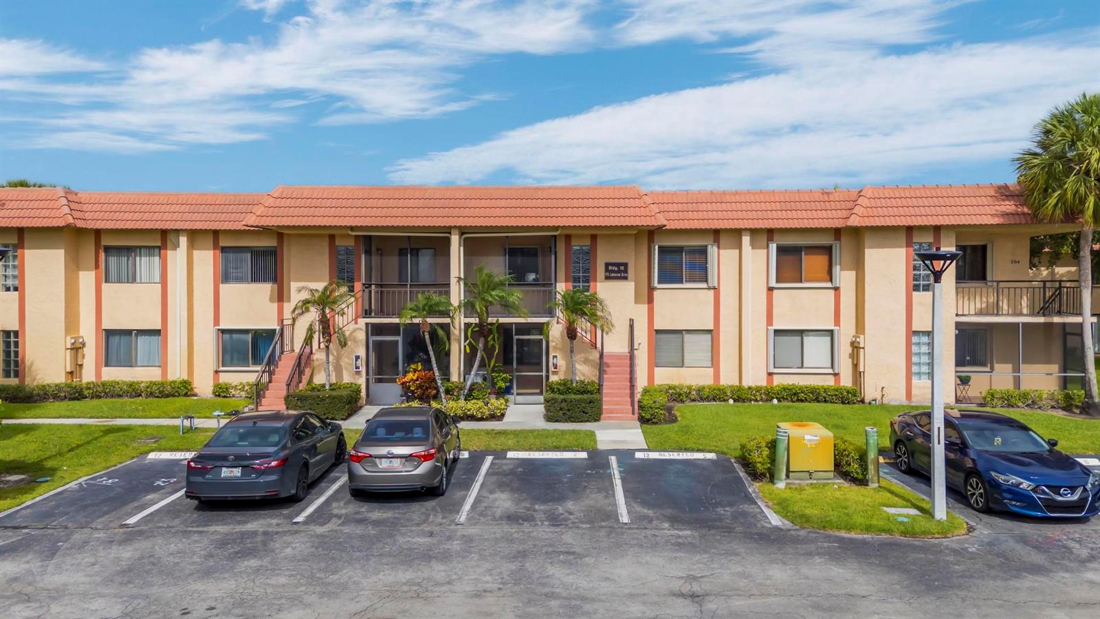 A two-story apartment building with a tiled roof, parking spaces, and palm trees in front — 170 Lakeview Drive # 203, Weston FL 33326, WESTON, FL
