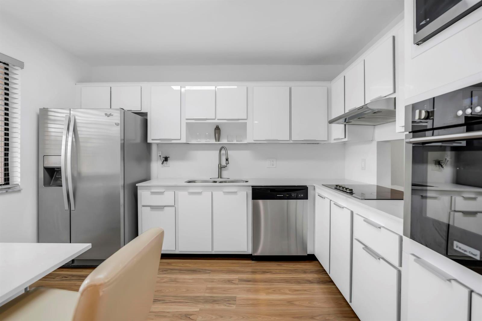 A modern kitchen features white cabinets, stainless steel appliances, and wood-look flooring — 170 Lakeview Drive # 203, Weston FL 33326, WESTON, FL