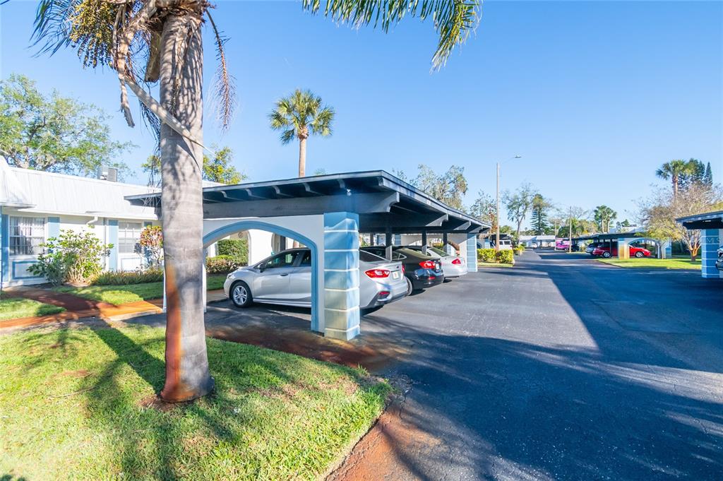 A covered parking carport with multiple parked cars sits beside a residential building — 4209 TAMARGO DRIVE UNIT 4209, NEW PORT RICHEY, FL