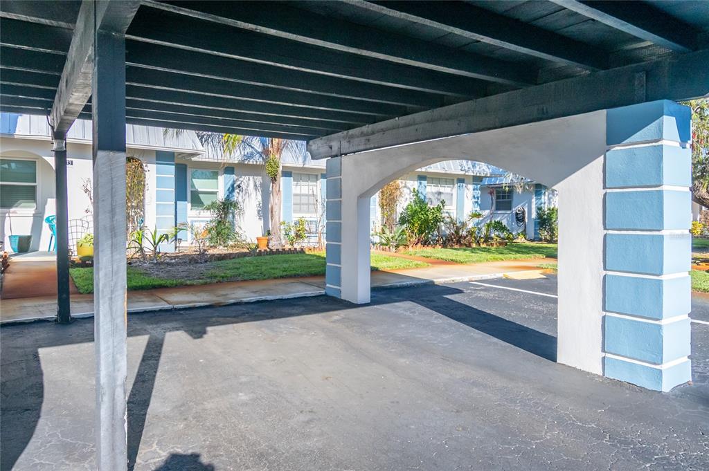 A covered carport with a white arched support pillar stands in front of a building — 4209 TAMARGO DRIVE UNIT 4209, NEW PORT RICHEY, FL