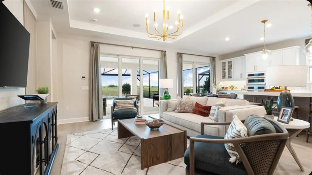 A living room with a sofa, armchairs, coffee table, and sliding doors leading to a patio — 26619 DOVE DRIVE, PUNTA GORDA, FL