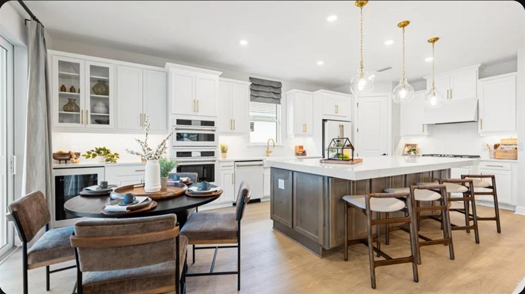 A bright kitchen features white cabinetry, a large gray island with bar seating, and dining area — 26619 DOVE DRIVE, PUNTA GORDA, FL