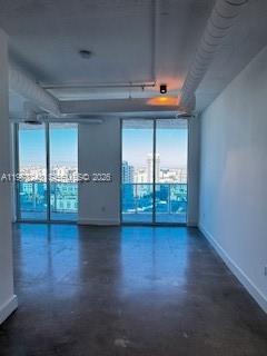 An empty room with polished concrete floors, exposed ceiling pipes, and large windows overlooking city buildings — 700 NE 25th St # 1701, Miami FL 33137, MIAMI, FL