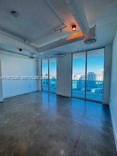 An empty room with concrete floors, exposed ceiling pipes, and a balcony overlooking the city — 700 NE 25th St # 1701, Miami FL 33137, MIAMI, FL