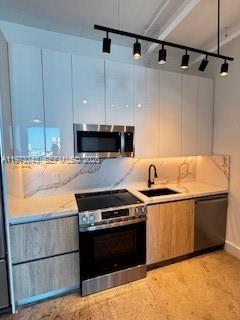 A modern kitchen features white upper cabinets, wood-tone lower cabinets, and a marble-patterned backsplash — 700 NE 25th St # 1701, Miami FL 33137, MIAMI, FL