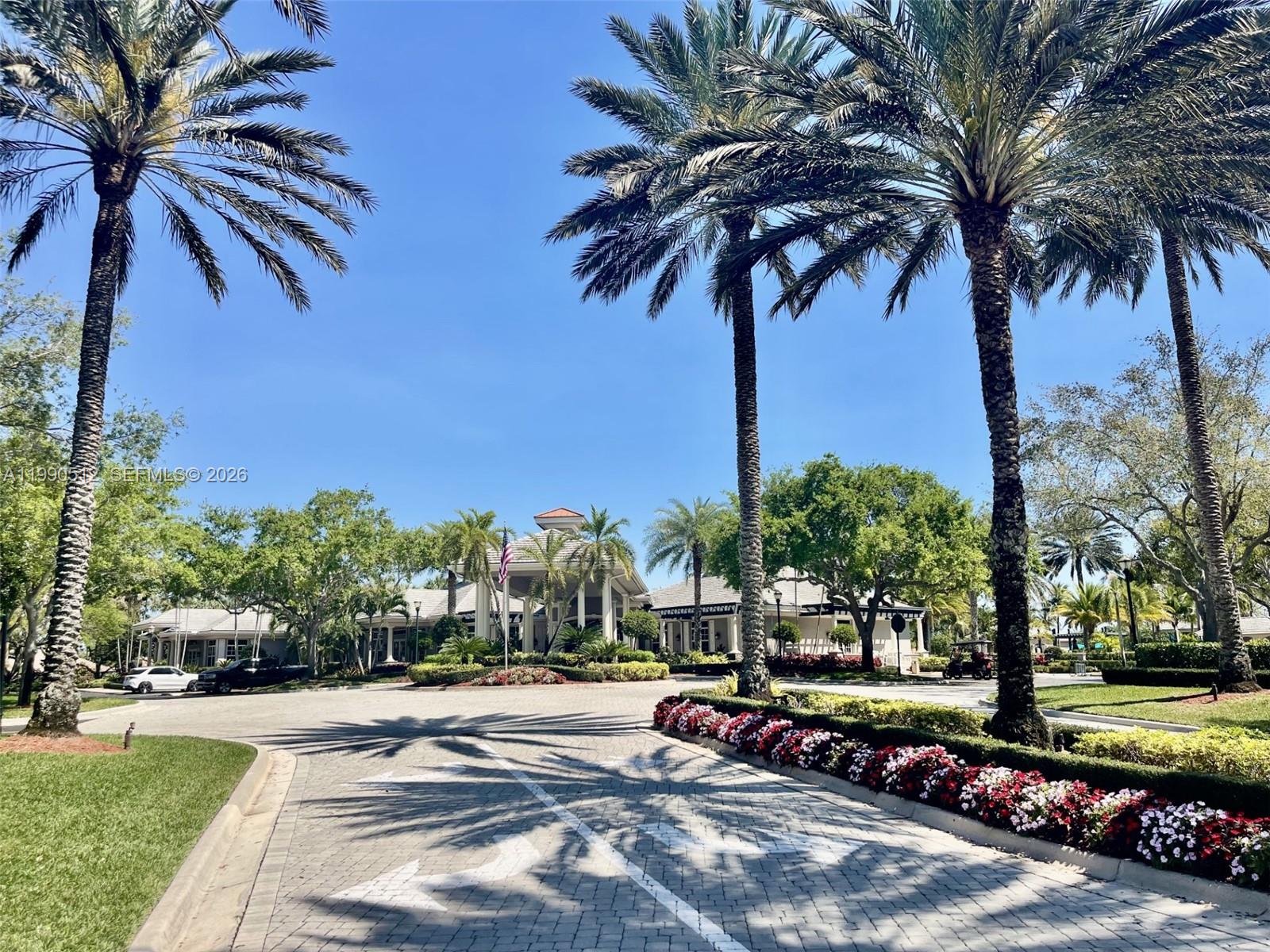 A paved driveway leads to a clubhouse entrance surrounded by palm trees and landscaping — 11289 NW 65th Mnr # 0, Parkland FL 33076, PARKLAND, FL