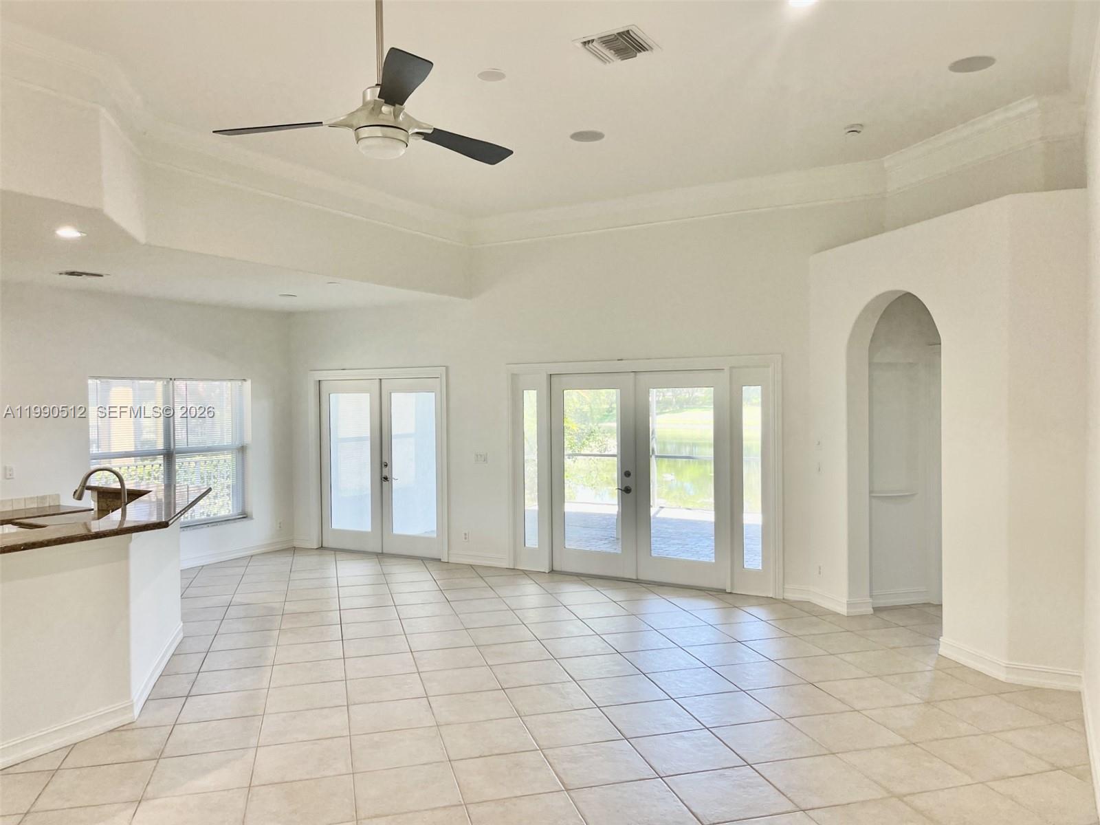 A bright, tiled living area features a tray ceiling, ceiling fan, and double glass doors — 11289 NW 65th Mnr # 0, Parkland FL 33076, PARKLAND, FL