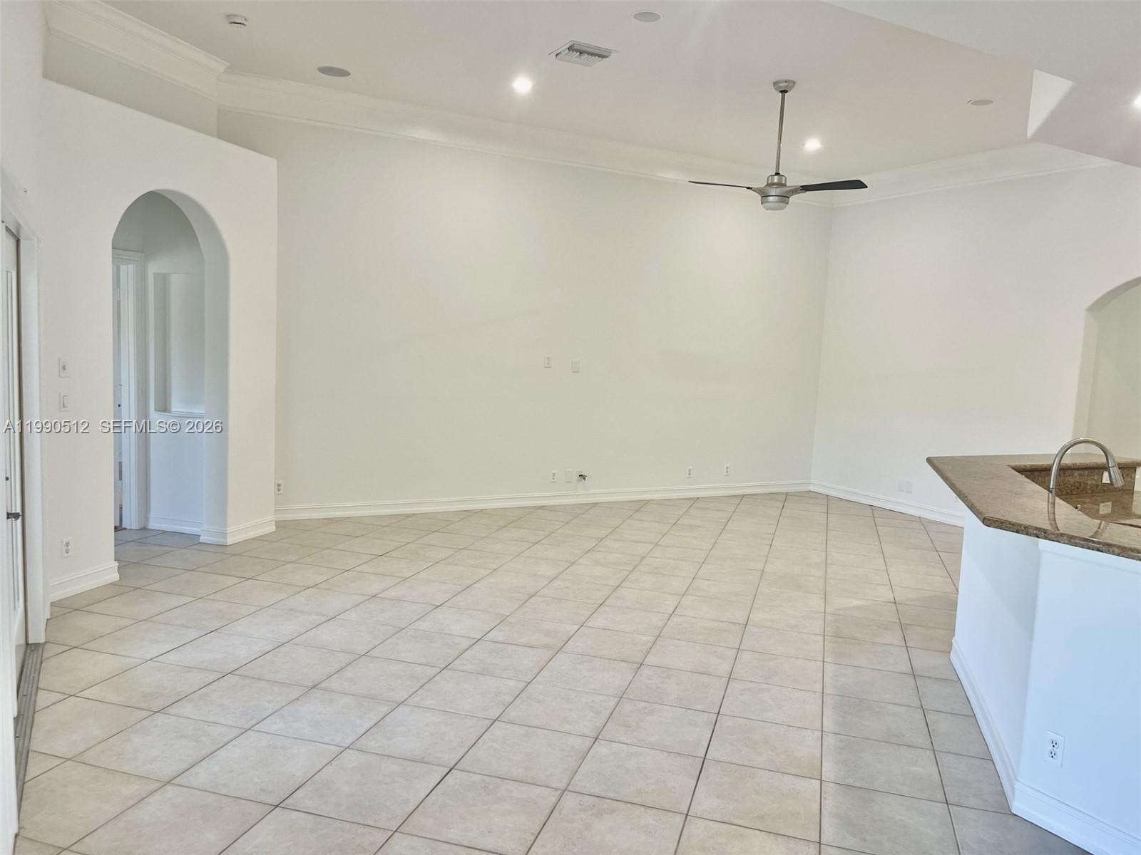 A spacious, empty living room features white walls, tile flooring, and a ceiling fan — 11289 NW 65th Mnr # 0, Parkland FL 33076, PARKLAND, FL