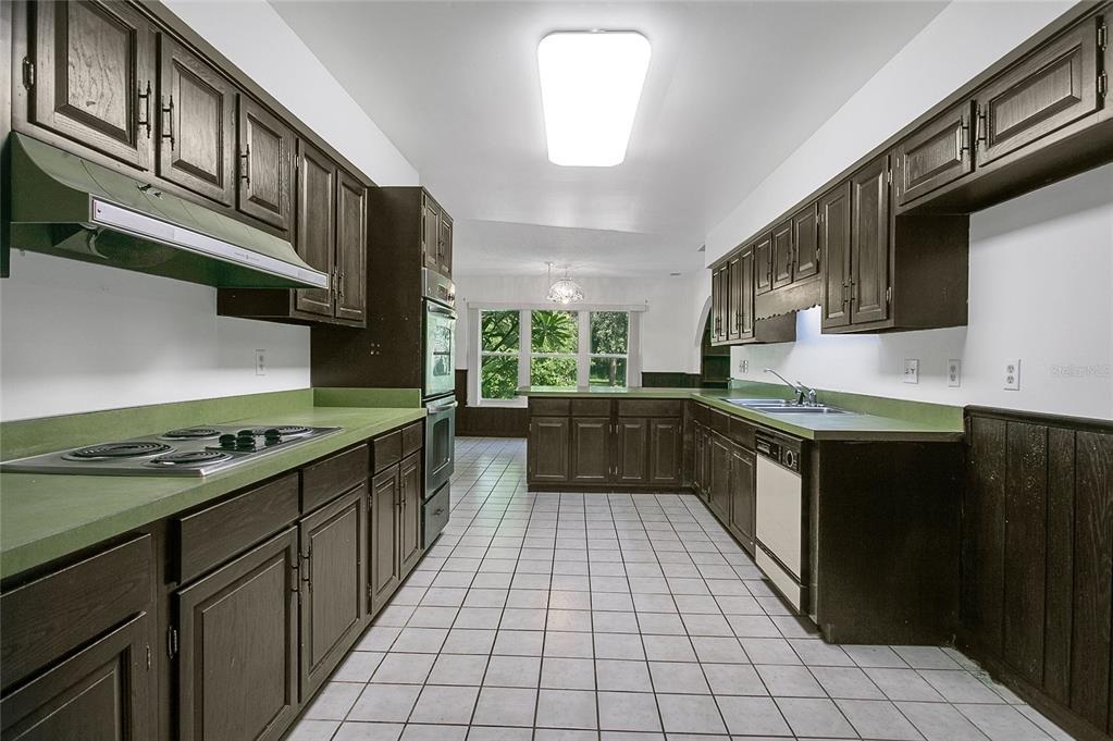 A galley kitchen features dark wood cabinets, green countertops, white tile floors, and a wall oven — 3629 LAKE BUYNAK ROAD, WINDERMERE, FL