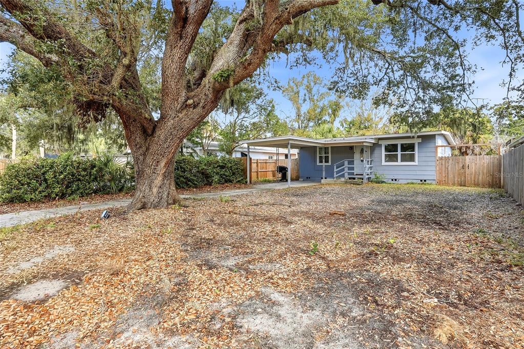 A single-story house with blue siding and a carport sits behind a large oak tree — 1137 40TH STREET, SARASOTA, FL