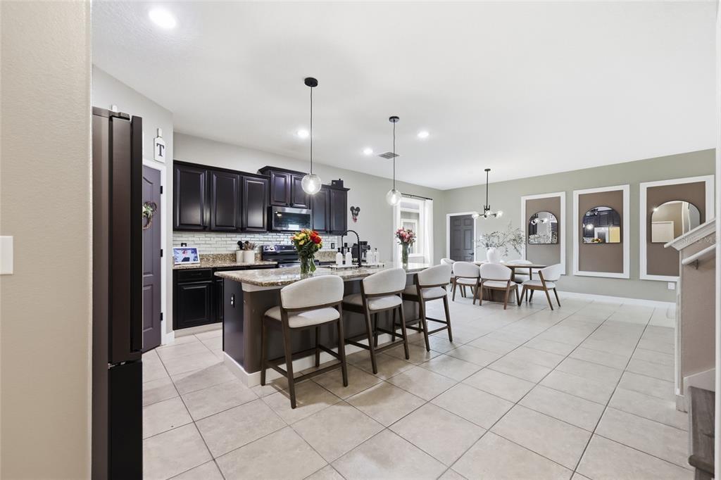 A kitchen with dark cabinets, granite countertops, and a center island with bar seating — 3420 SCHOOLHOUSE ROAD, ST CLOUD, FL
