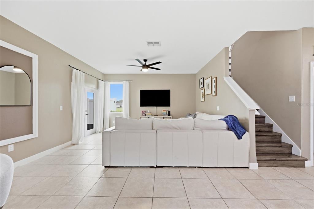 A living room features a white sectional sofa, tile flooring, and stairs to the right — 3420 SCHOOLHOUSE ROAD, ST CLOUD, FL