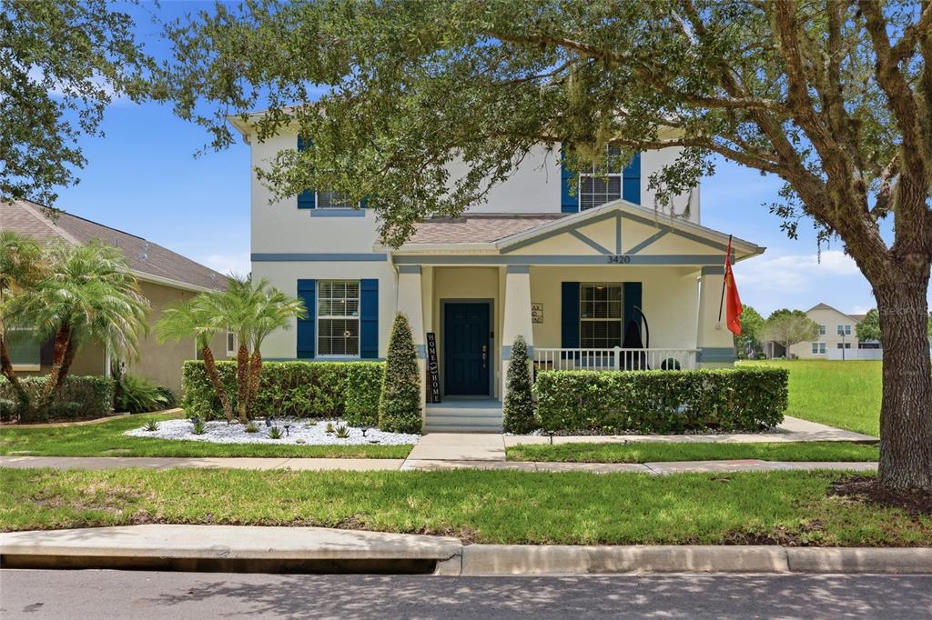 A two-story house with a covered front porch, blue shutters, and a landscaped front yard — 3420 SCHOOLHOUSE ROAD, ST CLOUD, FL