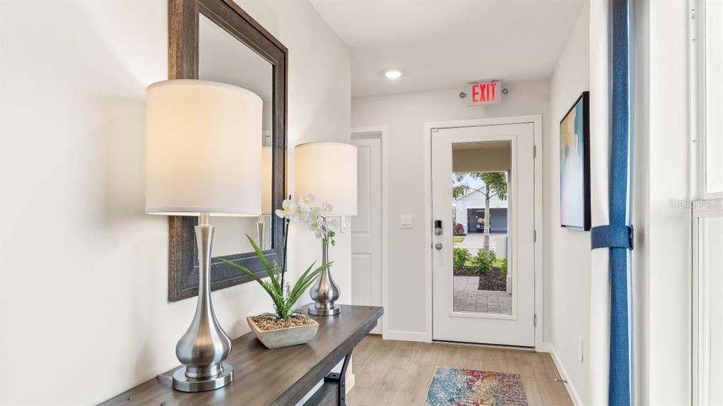 A brightly lit entryway features a console table with lamps, a mirror, and a glass-paneled door — 1517 HARMON DRIVE, PORT CHARLOTTE, FL