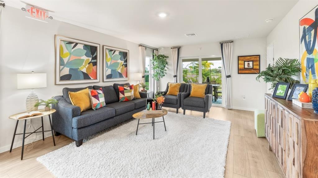 A living room features a gray sofa, two armchairs, a white rug, and wall art — 1517 HARMON DRIVE, PORT CHARLOTTE, FL