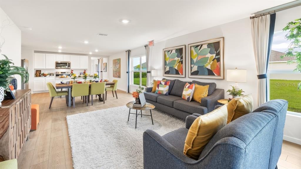 An open-concept living and dining area features a gray sofa, dining table, and kitchen — 1517 HARMON DRIVE, PORT CHARLOTTE, FL