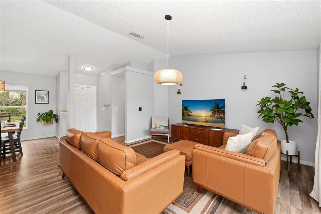 A living room features light gray walls, wood-look flooring, leather furniture, and a pendant light — 10826 SIENA DRIVE, CLERMONT, FL
