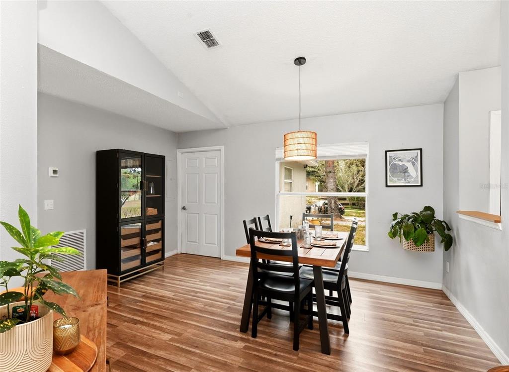 A dining room with wood-look flooring, a wooden table, black chairs, and a hanging pendant light — 10826 SIENA DRIVE, CLERMONT, FL