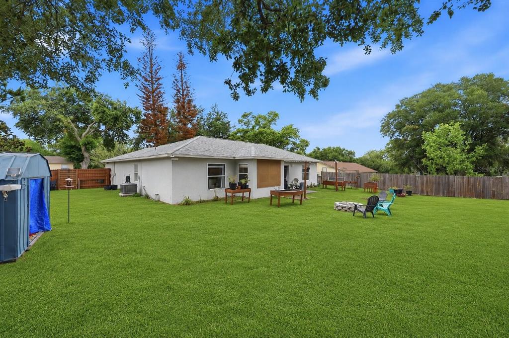 A backyard view of a single-story house with a lawn, fire pit, and wooden fence — 10826 SIENA DRIVE, CLERMONT, FL