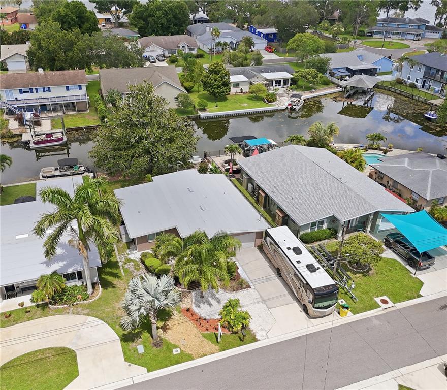 An aerial view shows waterfront houses with boat docks, a large RV, and palm trees — 179 E CANAL DRIVE, PALM HARBOR, FL