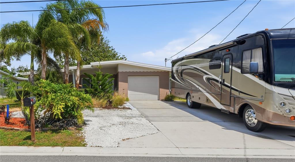 A single-story house with a garage and a large RV parked in the driveway — 179 E CANAL DRIVE, PALM HARBOR, FL