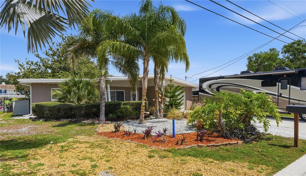 A single-story house with palm trees, a gravel yard, and a large RV parked nearby — 179 E CANAL DRIVE, PALM HARBOR, FL