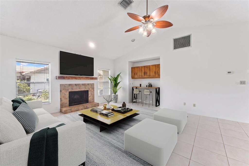 A living room features a stone fireplace, a wooden mantel, a bar area, and tile flooring — 5415 BAY SIDE DRIVE, ORLANDO, FL