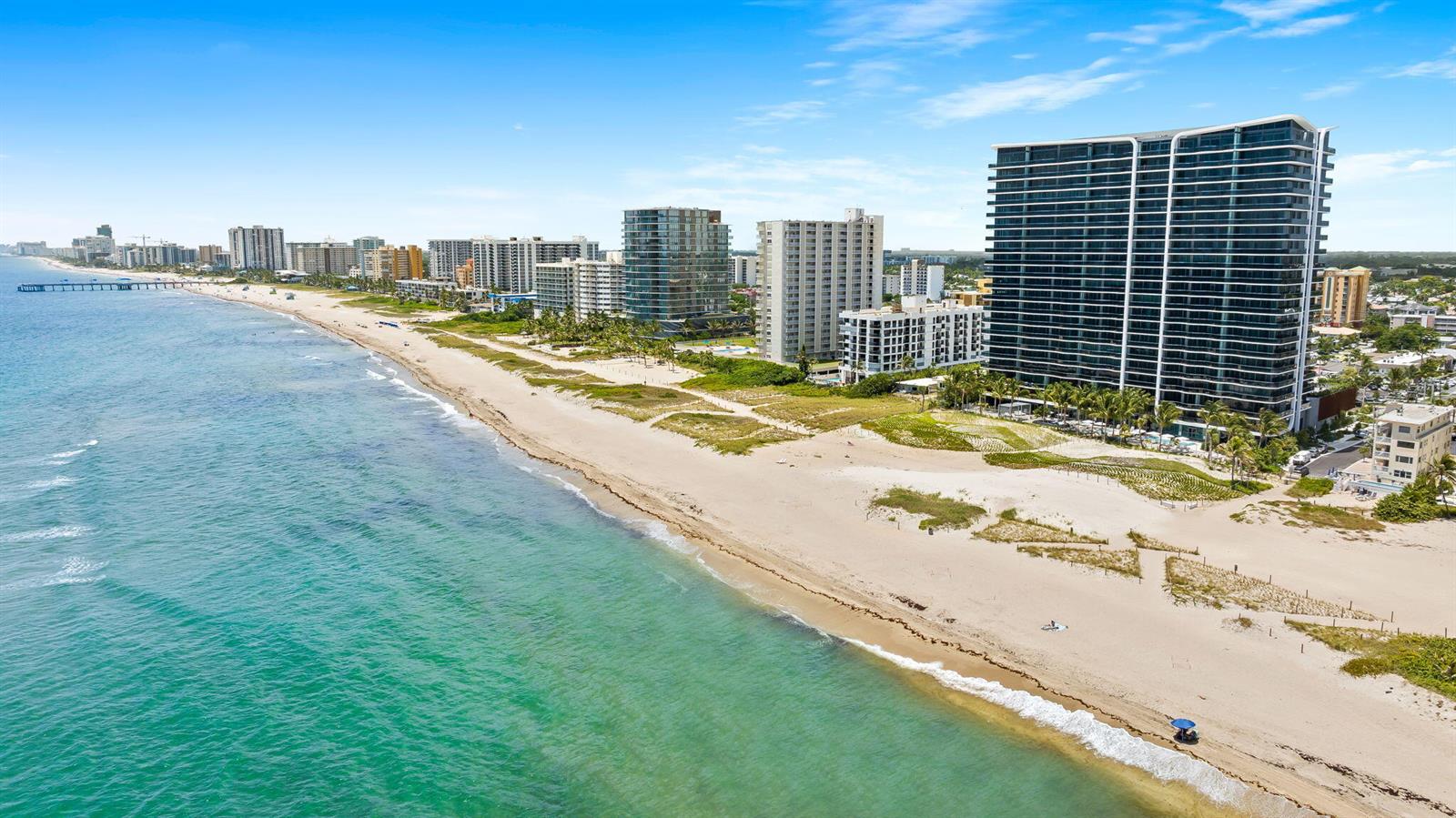 An aerial view of a sandy beach lined with high-rise residential buildings and a pier — 900 N Ocean Boulevard # 906, Pompano Beach FL 33062, POMPANO BEACH, FL