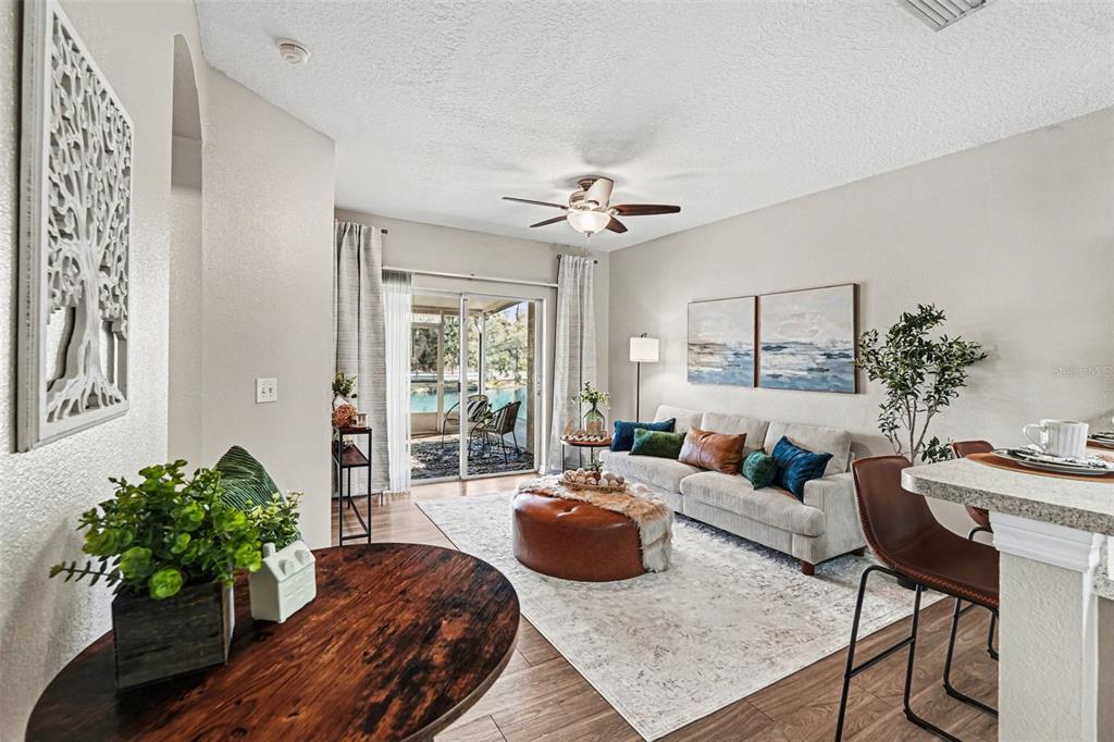 A living room features a sofa, leather ottoman, and sliding glass doors leading to a patio — 3342 BROKEN BOW DRIVE, LAND O LAKES, FL