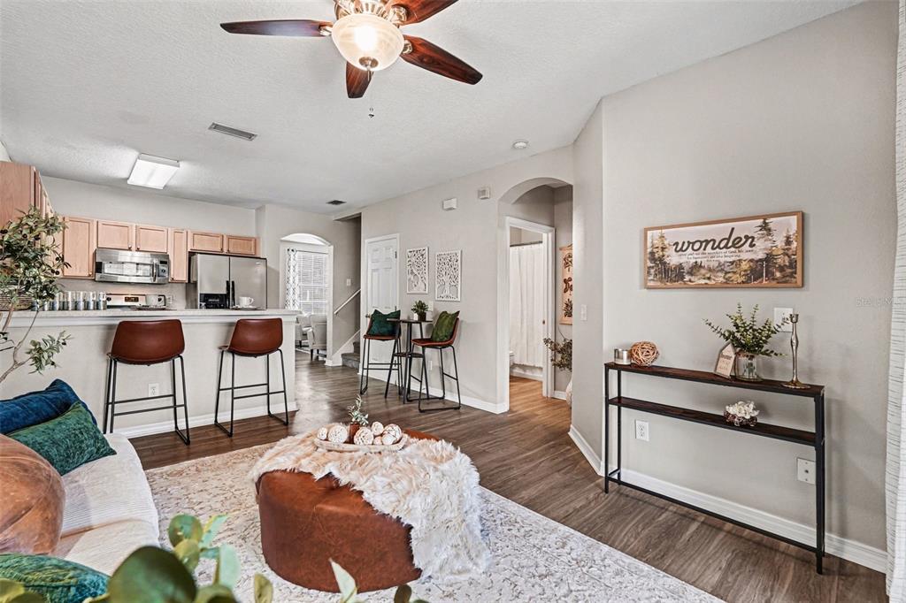 A living room with wood-look flooring, a kitchen breakfast bar, and a console table — 3342 BROKEN BOW DRIVE, LAND O LAKES, FL