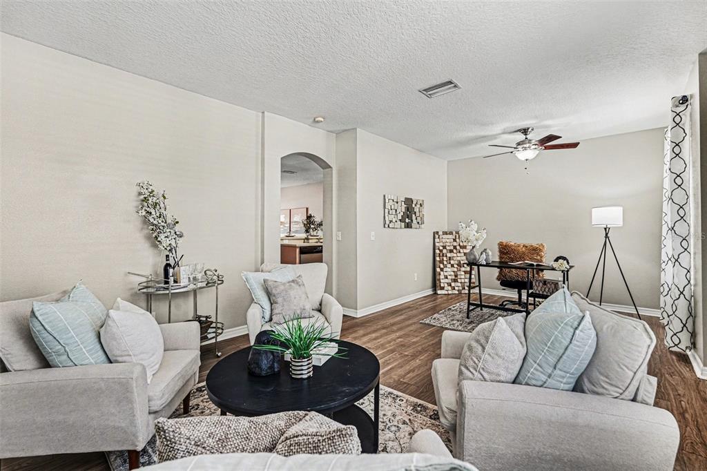 A living room with light-colored furniture, a round coffee table, and a desk area — 3342 BROKEN BOW DRIVE, LAND O LAKES, FL