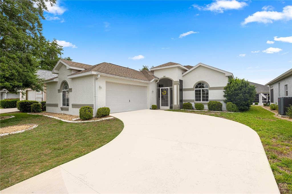 A single-story house with a white stucco exterior, a two-car garage, and a curved driveway — 2379 NW 55TH AVENUE ROAD, OCALA, FL