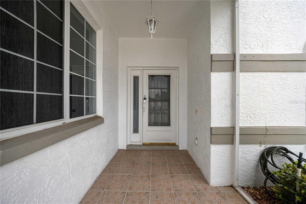A covered front porch with tiled flooring leads to a white front door and window — 2379 NW 55TH AVENUE ROAD, OCALA, FL