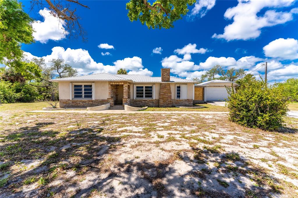A single-story house with a metal roof, brick accents, and an attached garage — 12500 PLACIDA ROAD, PLACIDA, FL