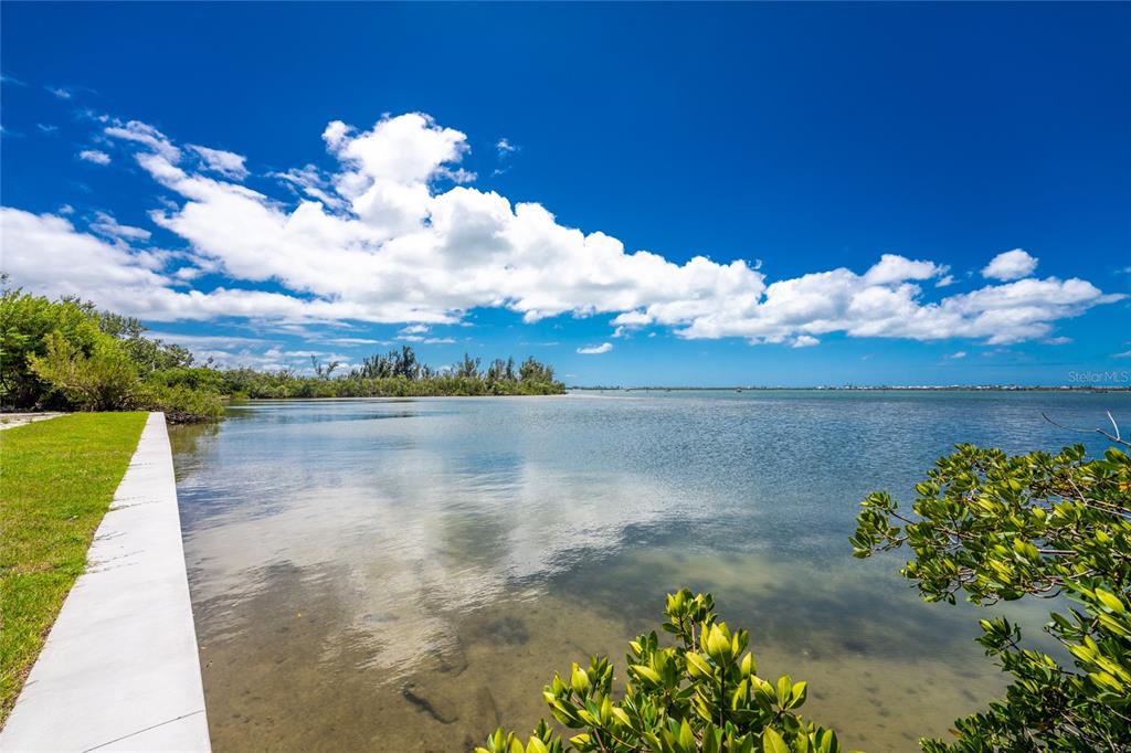 A concrete walkway borders a calm bay with mangroves and a bright blue sky — 12500 PLACIDA ROAD, PLACIDA, FL