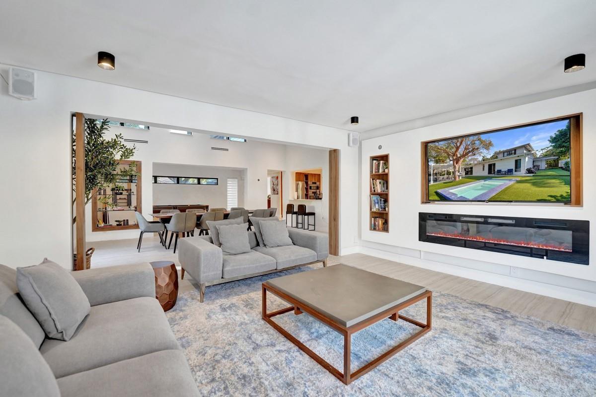 A living room with a fireplace, wall-mounted television, gray sofas, and an adjacent dining area — 4417 SW 38th Terrace, Dania Beach FL 33312, DANIA BEACH, FL