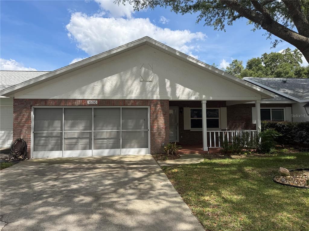 A single-story home with a brick facade, a screened garage door, and a front porch — 9529 SW 85TH AVENUE UNIT D, OCALA, FL