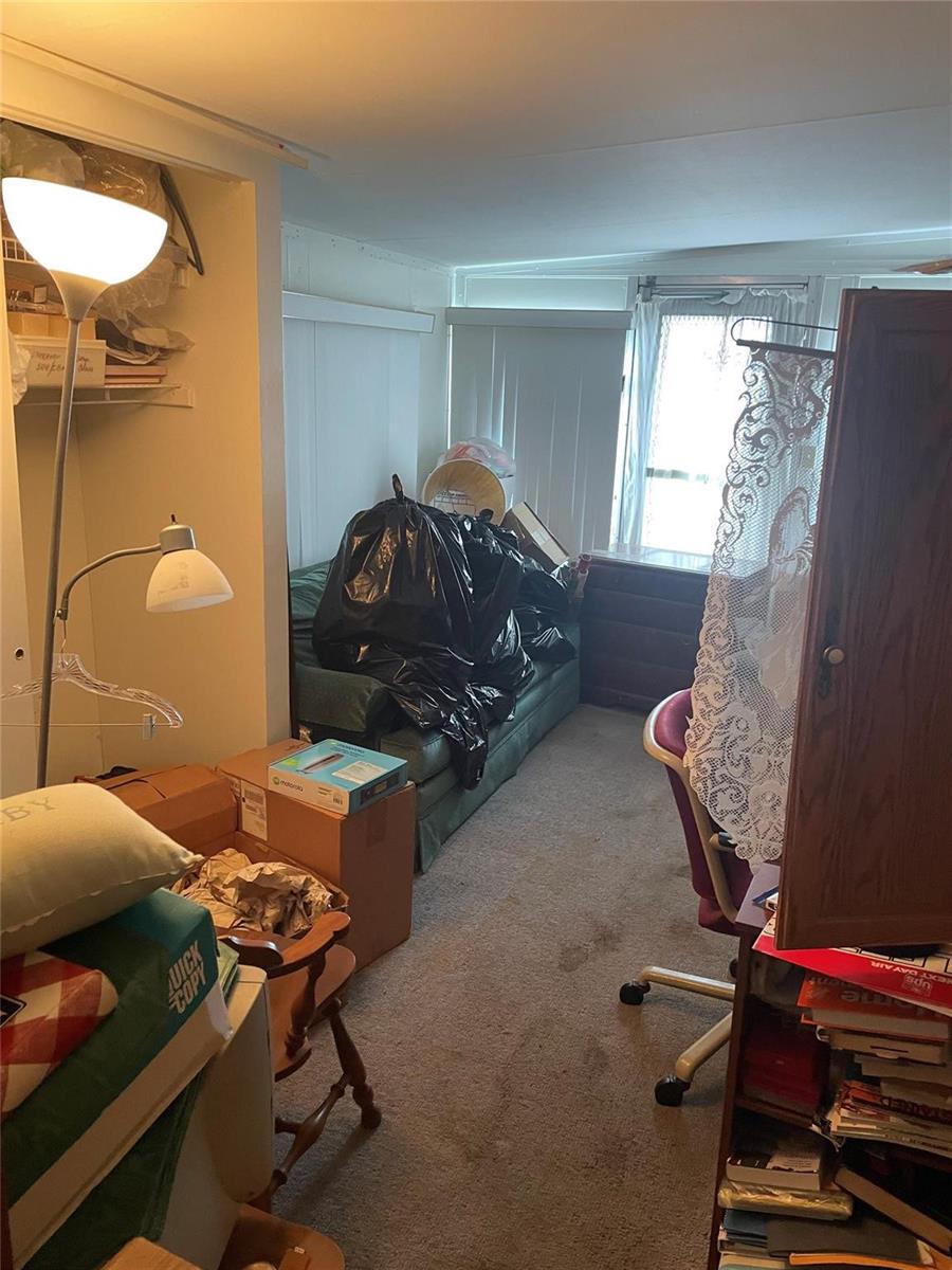 A cluttered room features a green sofa, a desk, a floor lamp, and carpeted flooring — 8581 SW 20th Place, Davie FL 33324, DAVIE, FL