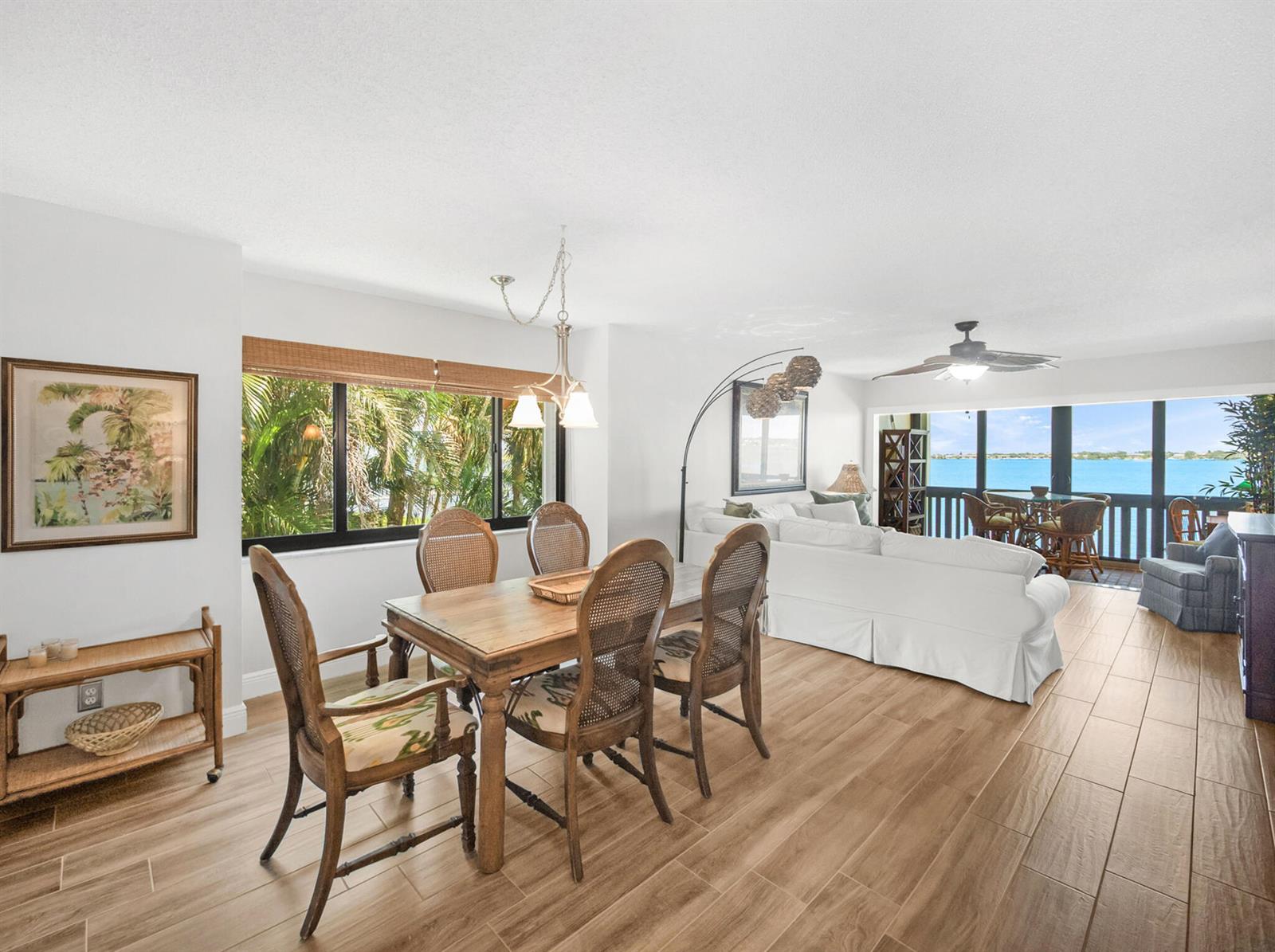 A dining area and living room with wood-look tile floors overlook a balcony and water — 175 SE Saint Lucie Boulevard # F116, Stuart FL 34996, STUART, FL