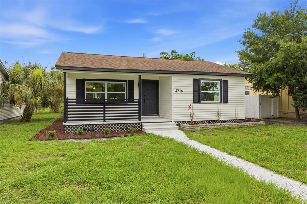 A single-story house with light siding, black shutters, and a front porch with horizontal railings — 4716 17TH AVENUE N, ST PETERSBURG, FL