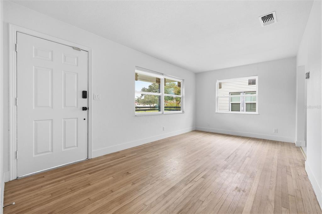 A bright living room features white walls, light wood flooring, and two windows — 4716 17TH AVENUE N, ST PETERSBURG, FL