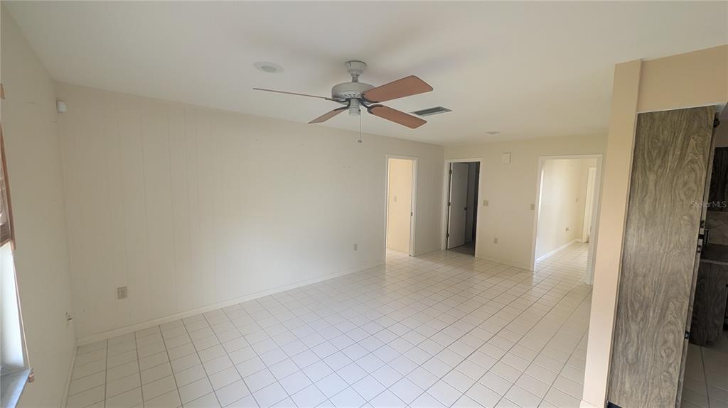 A room with white tiled floors, a ceiling fan, and three doorways leading elsewhere — 3720 PIN OAKS STREET, SARASOTA, FL