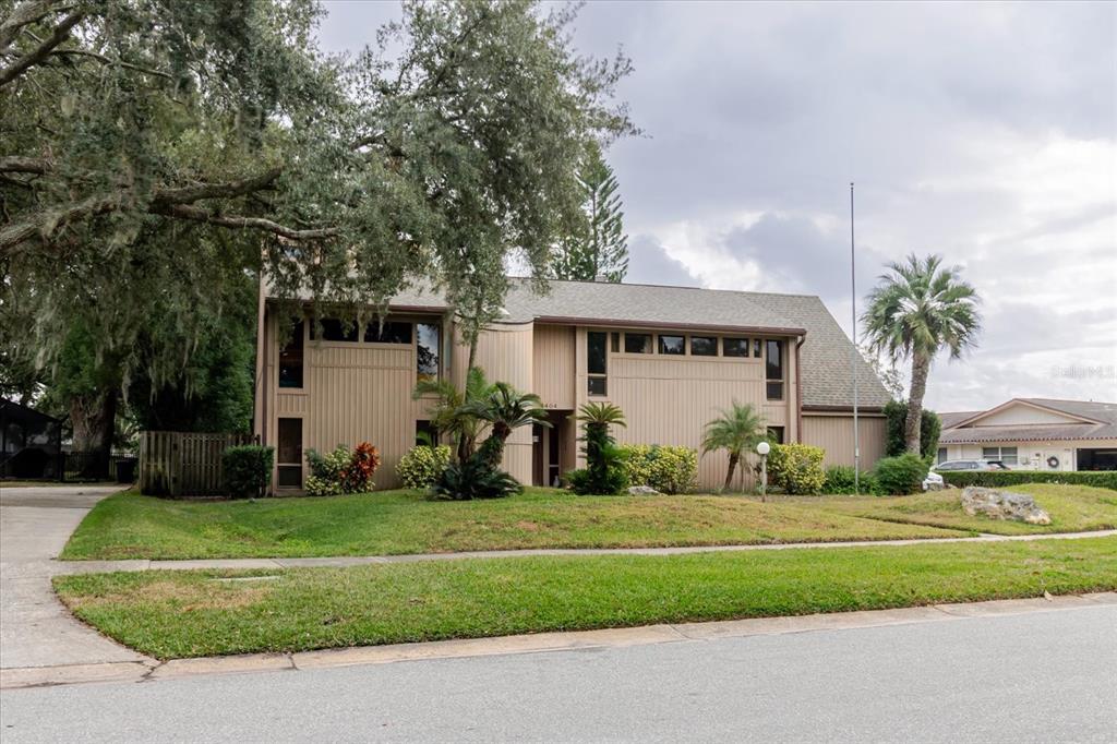 A two-story house with tan vertical siding and a large tree in the front yard — 4404 OLD ORCHARD DRIVE, TAMPA, FL