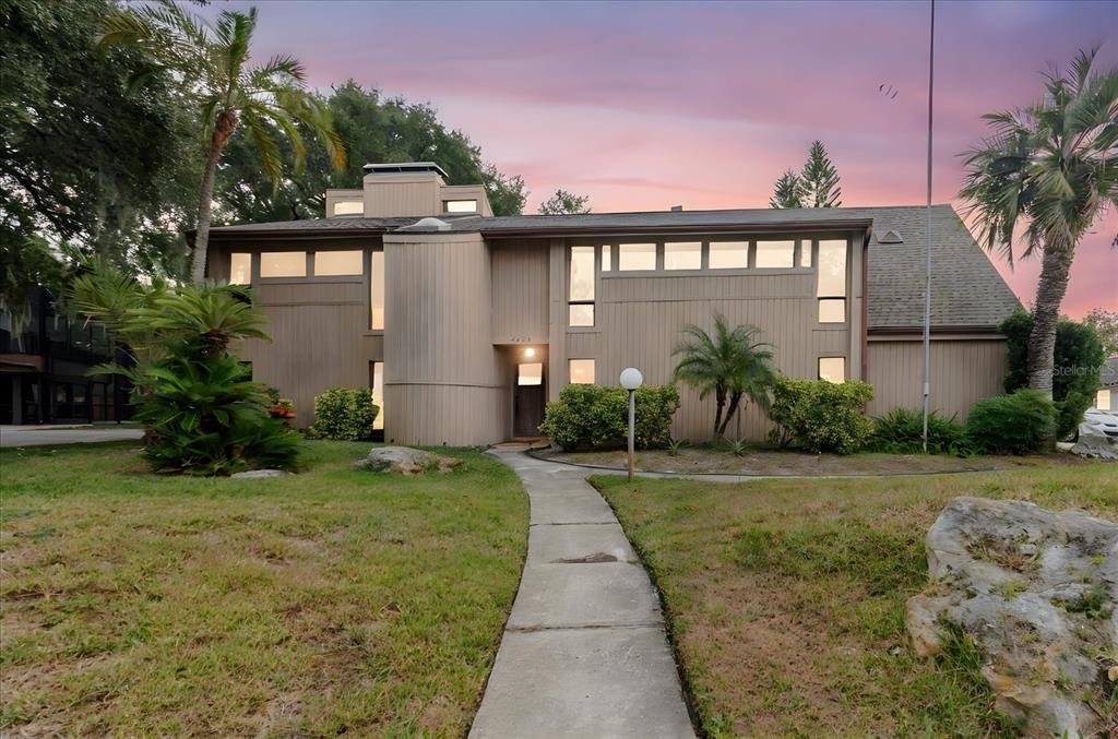 A two-story house with vertical wood siding and a concrete walkway leading to the entrance — 4404 OLD ORCHARD DRIVE, TAMPA, FL