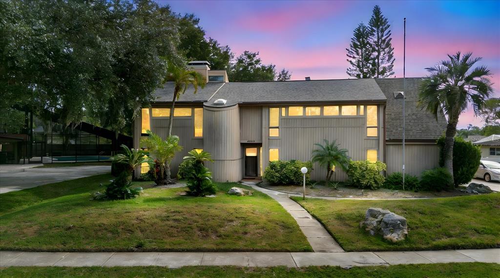 A two-story house with vertical siding, a curved entryway, and a front lawn at dusk — 4404 OLD ORCHARD DRIVE, TAMPA, FL
