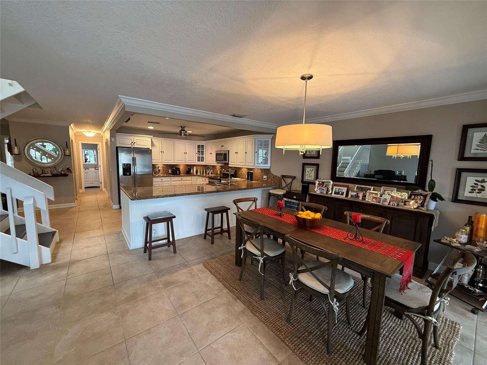 A kitchen with white cabinets and granite countertops opens to a dining area with seating — 22861 Ironwedge Drive, Boca Raton FL 33433, BOCA RATON, FL