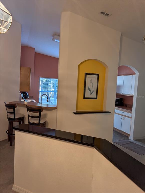 A kitchen features a breakfast bar, a yellow arched wall niche, and white cabinetry — 140 GRAND CANAL DRIVE, KISSIMMEE, FL