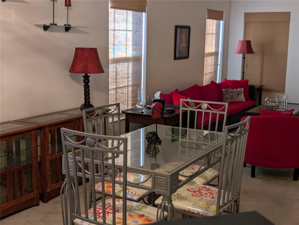 A dining area with a glass-topped table and metal chairs sits before a living room — 140 GRAND CANAL DRIVE, KISSIMMEE, FL