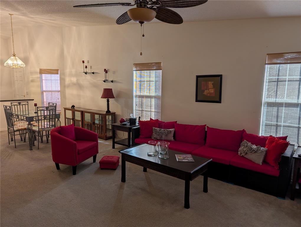 A living room features a red sofa, a matching armchair, and an adjacent dining area — 140 GRAND CANAL DRIVE, KISSIMMEE, FL